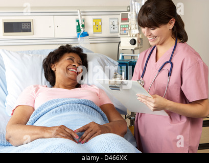 Nurse Visiting Senior Female Patient On Ward Stock Photo