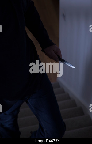 Shadowy male intruder holding a knife. Stock Photo