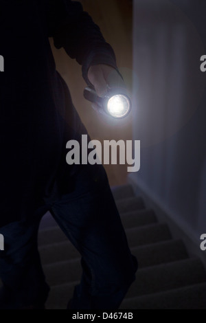 Shadowy male intruder holding a torch or flash light Stock Photo