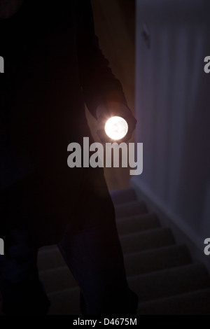 Shadowy male intruder holding a torch or flash light Stock Photo