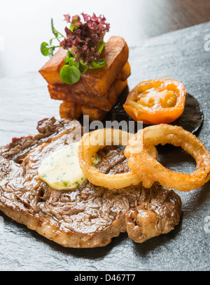 Steak and onion rings, served with chunky chips Stock Photo