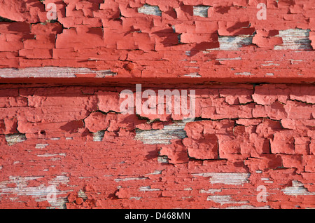 Close-up of red paint peeling off wooden clapboards Stock Photo