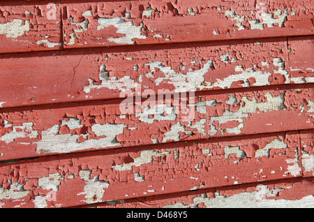 Red paint peeling off wooden clapboard siding Stock Photo