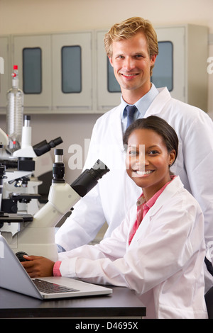 Male And Female Scientists Using Microscopes In Laboratory Stock Photo