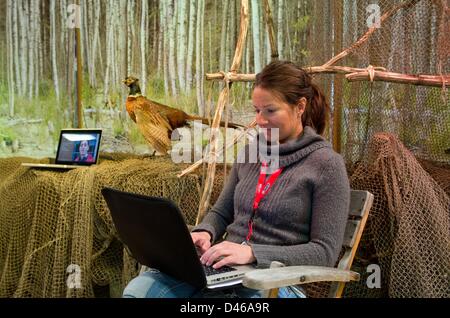 Berlin, Germany. 6th March 2013. A trade show employee sits with her laptop at the exhibition booth of Adventure Travel ATTA on the opening day of the tourism trade fair ITB Berlin (Internationale Tourismus Boerse) in Berlin. The travel trade fair will take place from 06 till 10 March 2013 at the trade fair halls under the radio tower. This year'S official partner nation is Indonesia. Photo: SOEREN STACHE/dpa/Alamy Live News Stock Photo