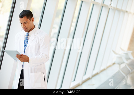 Doctor Using Digital Tablet In Corridor Of Modern Hospital Stock Photo