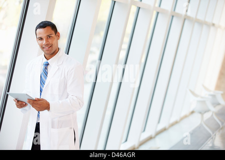 Doctor Using Digital Tablet In Corridor Of Modern Hospital Stock Photo