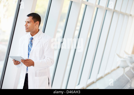 Doctor Using Digital Tablet In Corridor Of Modern Hospital Stock Photo