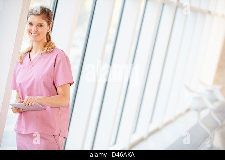 Nurse Using Digital Tablet In Corridor Of Modern Hospital Stock Photo