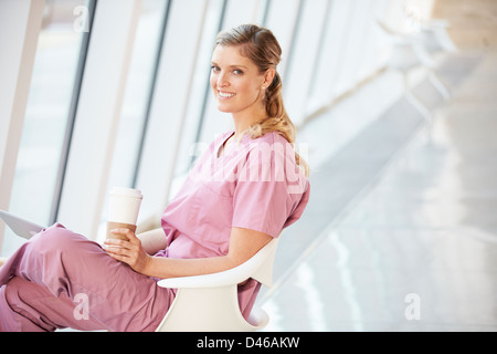 Female Nurse Using Digital Tablet On Coffee Break In Hospital Stock Photo