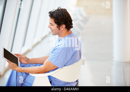 Male Nurse Sitting In Chair Using Digital Tablet Stock Photo