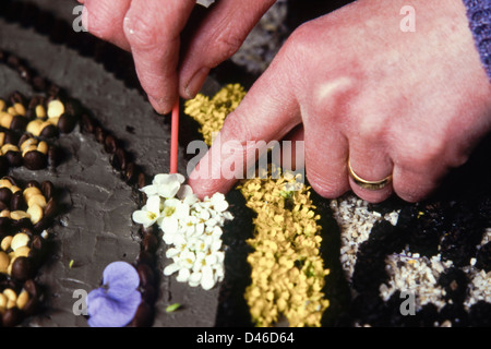 Well Dressing at Etwall Derbyshire England UK closeup detail of woman inserting flower petals into a display Stock Photo