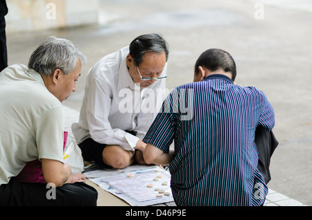 Elderly Chinese men playing an ancient form of Chinese chess, xiangqi, in a public park during their free time Stock Photo