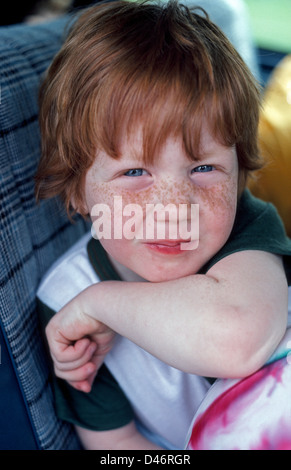 A young red-headed freckle-faced American boy smiles at the camera. Stock Photo