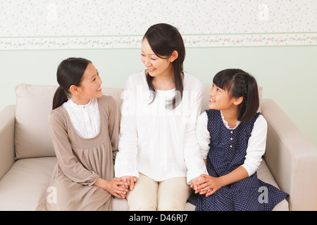 Mother And Daughters Sitting On the Sofa Stock Photo