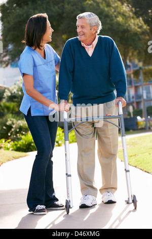 Carer Helping Senior Man With Walking Frame Stock Photo