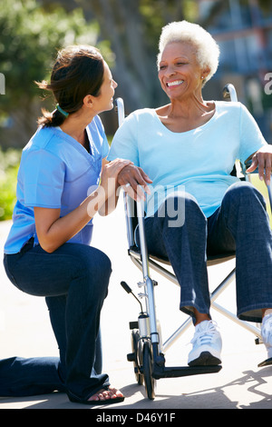 Carer Pushing Senior Woman In Wheelchair Stock Photo