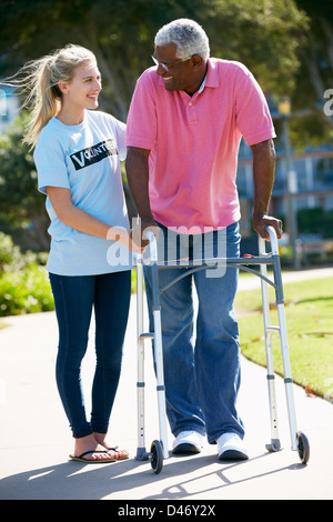 Teenage Volunteer Helping Senior Man With Walking Frame Stock Photo