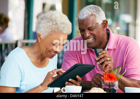Senior Couple Using Tablet Computer At Outdoor Café Stock Photo