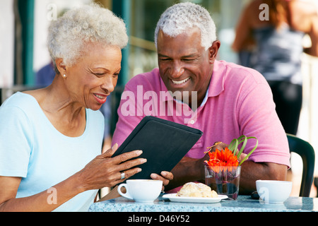 Senior Couple Using Tablet Computer At Outdoor Café Stock Photo