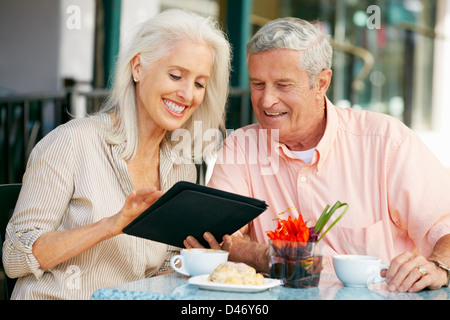 Senior Couple Using Tablet Computer At Outdoor Café Stock Photo