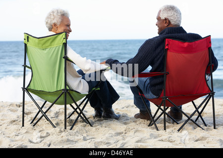 Senior Couple Sitting On Beach In Deckchairs Stock Photo