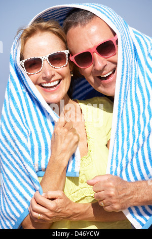 Senior Couple Sheltering From Sun On Beach Holiday Stock Photo