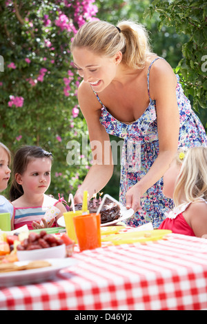Mother Serving Birthday Cake To Group Of Children Outdoors Stock Photo