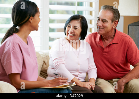 Nurse Making Notes During Home Visit With Senior Couple Stock Photo