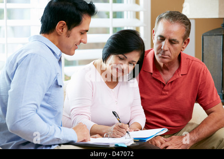 Financial Advisor Talking To Senior Couple At Home Stock Photo