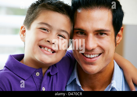 Portrait Of Father And Son Sitting On Sofa At Home Stock Photo