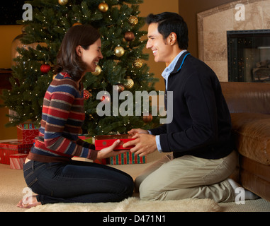 Couple Opening Presents In Front Of Christmas Tree Stock Photo