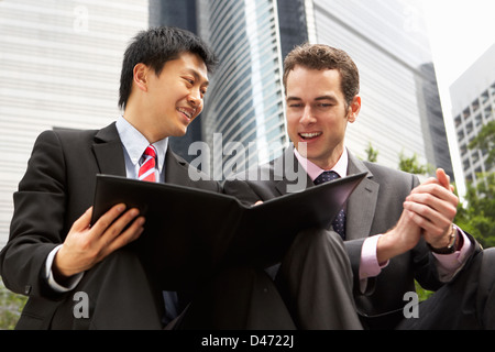 Two Businessmen Discussing Document Outside Office Stock Photo