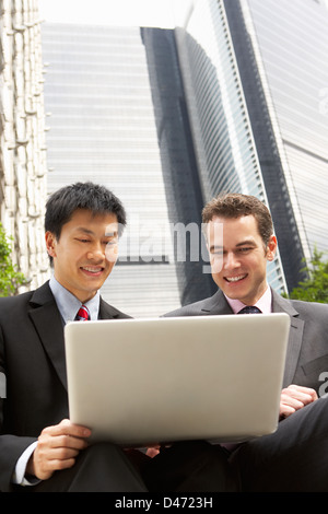 Portrait Of Two Businessmen Working On Laptop Outside Office Stock Photo