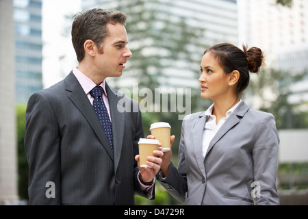 Businessman And Businesswoman Chatting In Street Holding Takeaway Coffee Stock Photo