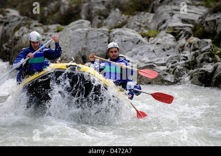 Young tourists practice rafting with a guide in Sella river in an inflatable boat in Asturias, Spain. Stock Photo