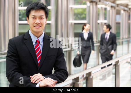 Portrait Of Chinese Businessman Outside Office With Colleagues In Background Stock Photo