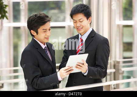 Two Chinese Businessmen Using Tablet Computer Outside Office Stock Photo