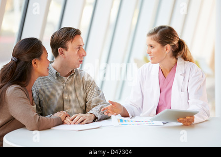 Female Doctor Using Digital Tablet Talking With Patients Stock Photo