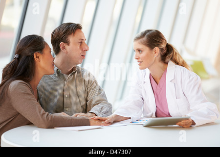 Female Doctor Using Digital Tablet Talking With Patients Stock Photo