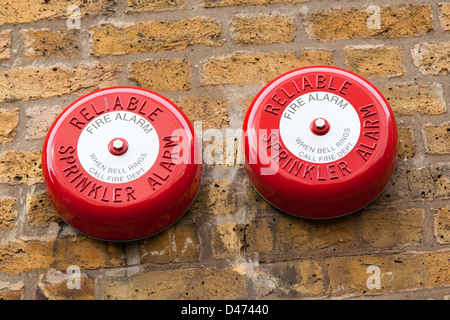 Two fire alarm bells mounted on a brick wall Stock Photo