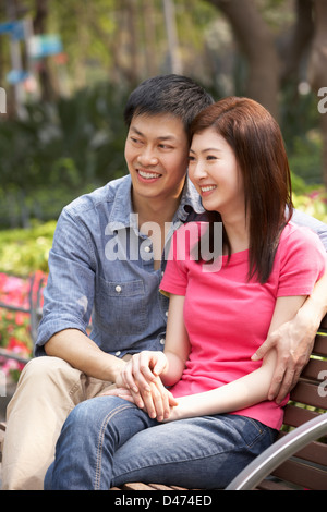 Young Chinese Couple Relaxing On Park Bench Together Stock Photo