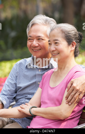 Senior Chinese Couple Relaxing On Park Bench Together Stock Photo