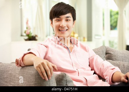 Young Chinese Man Relaxing On Sofa At Home Stock Photo