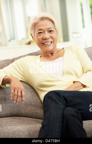 Senior Chinese Woman Relaxing On Sofa At Home Stock Photo