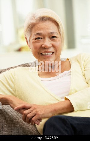 Senior Chinese Woman Relaxing On Sofa At Home Stock Photo