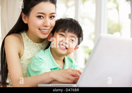 Chinese Mother And Son Sitting At Desk Using Laptop At Home Stock Photo