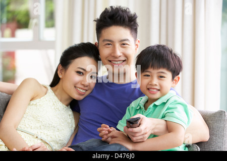 Chinese Family Sitting And Watching TV On Sofa Together Stock Photo