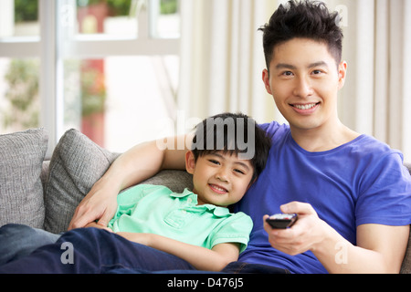 Chinese Father And Son Sitting And Watching TV On Sofa Together Stock Photo