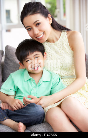 happy asian mother and son sitting on family couch at home taking a